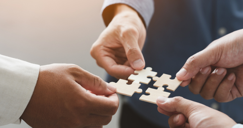 Business people team holds in hand a jigsaw or puzzle pieces in the office for concept of troubleshooting