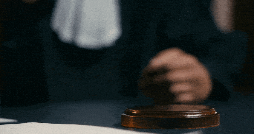 Close-up hand of judge striking gavel, calling courtroom public to order