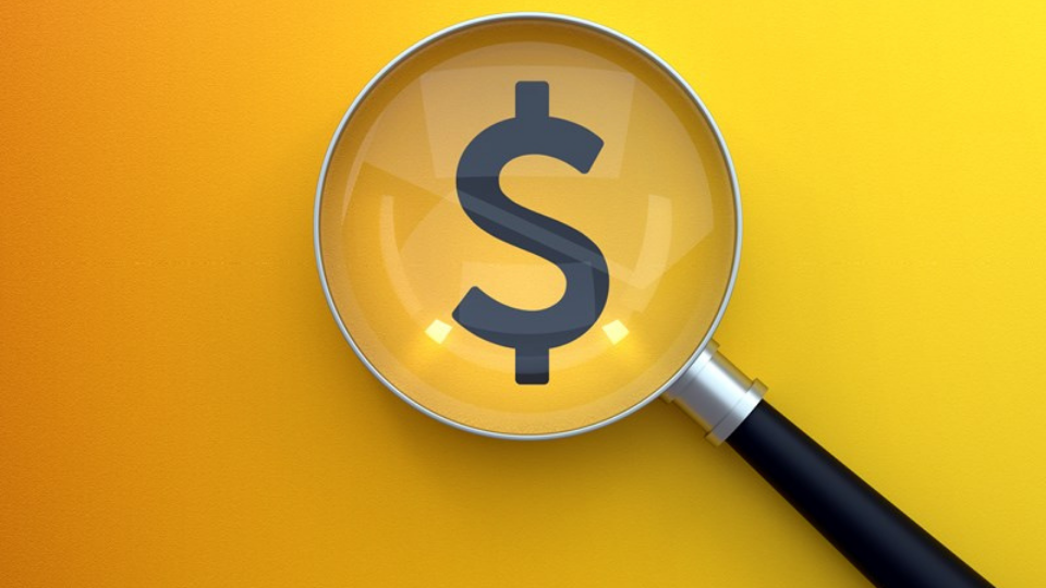 Magnifying glass over a dollar sign on yellow
