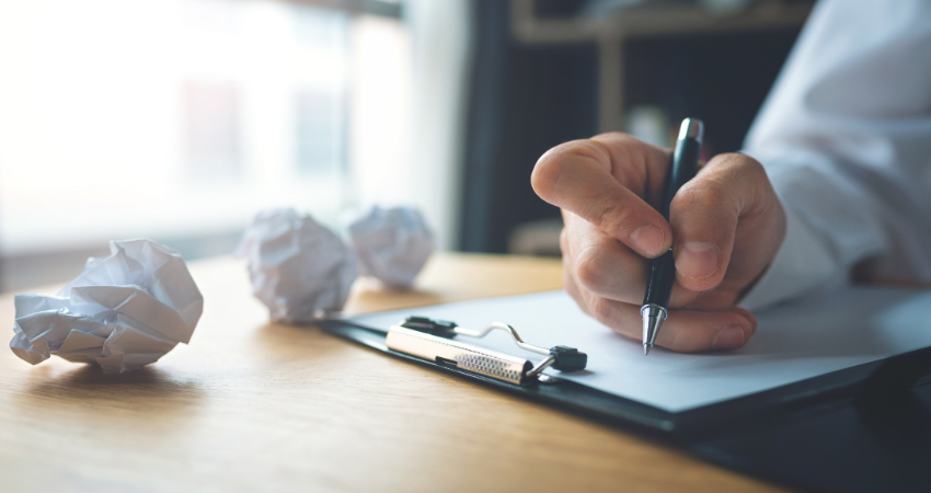Businessman writing on the table with paper balls