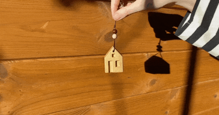 Miniature model of a wooden house in a woman's hand in sunlight