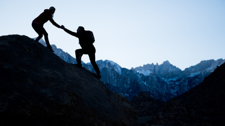 Couple helping each other in the mountains