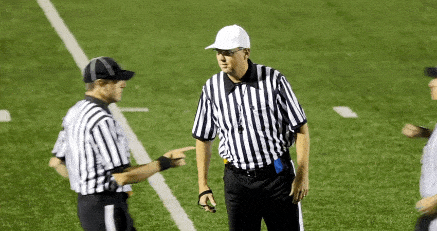 Three refs discuss a foul on the field