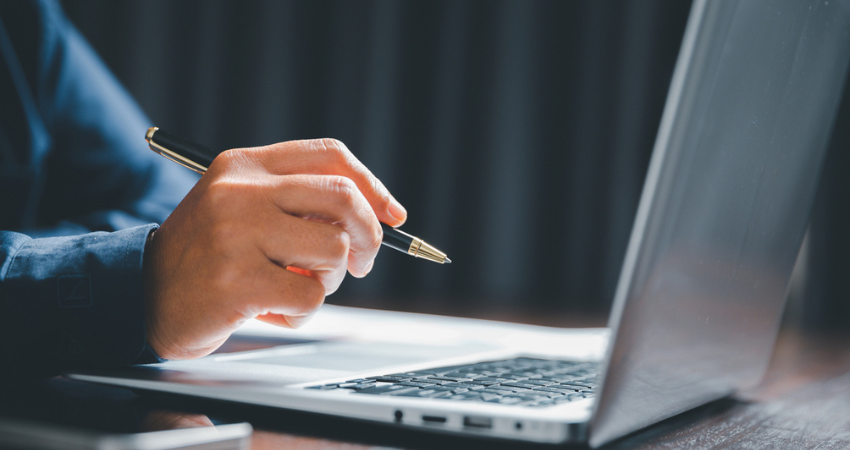 Closeup of businesswoman typing on laptop computer while sitting on table in office for design work