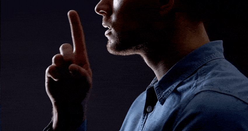 Man gesturing silence isolated on black