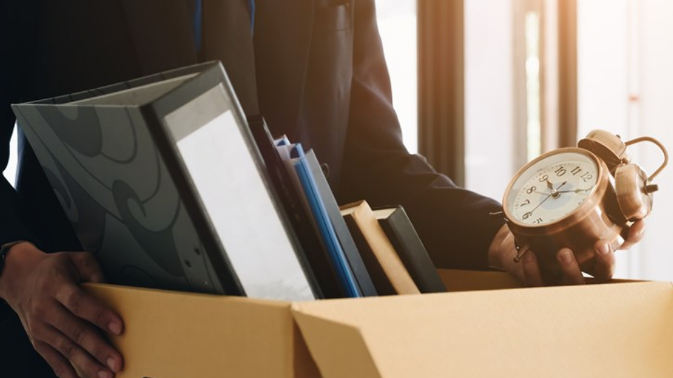 Businessman fired, leaving his office with his personal effects