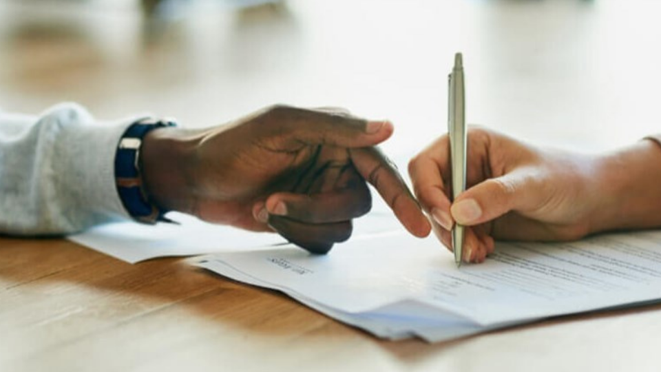 Person signing document with pen