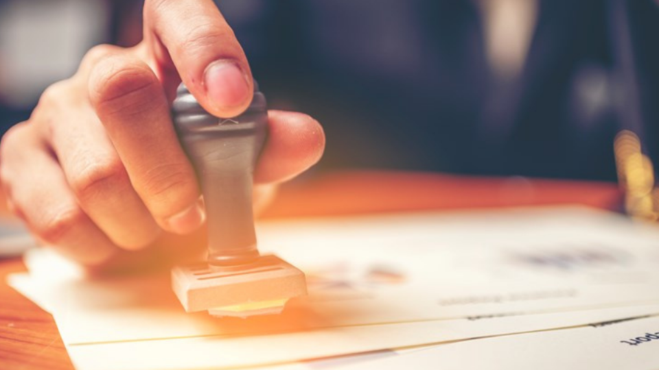 Close-up hand stamping of businessman for signing approval on documents